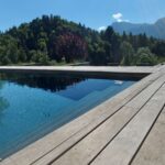 Piscine moderne avec terrasse en bois et vue panoramique sur les montagnes