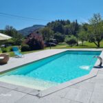 Piscine moderne construite par Dodin Piscine avec plage en pierre et cascade design