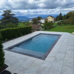 Piscine moderne avec margelles en grès cérame et vue panoramique sur la campagne, réalisée par Dodin Piscine.